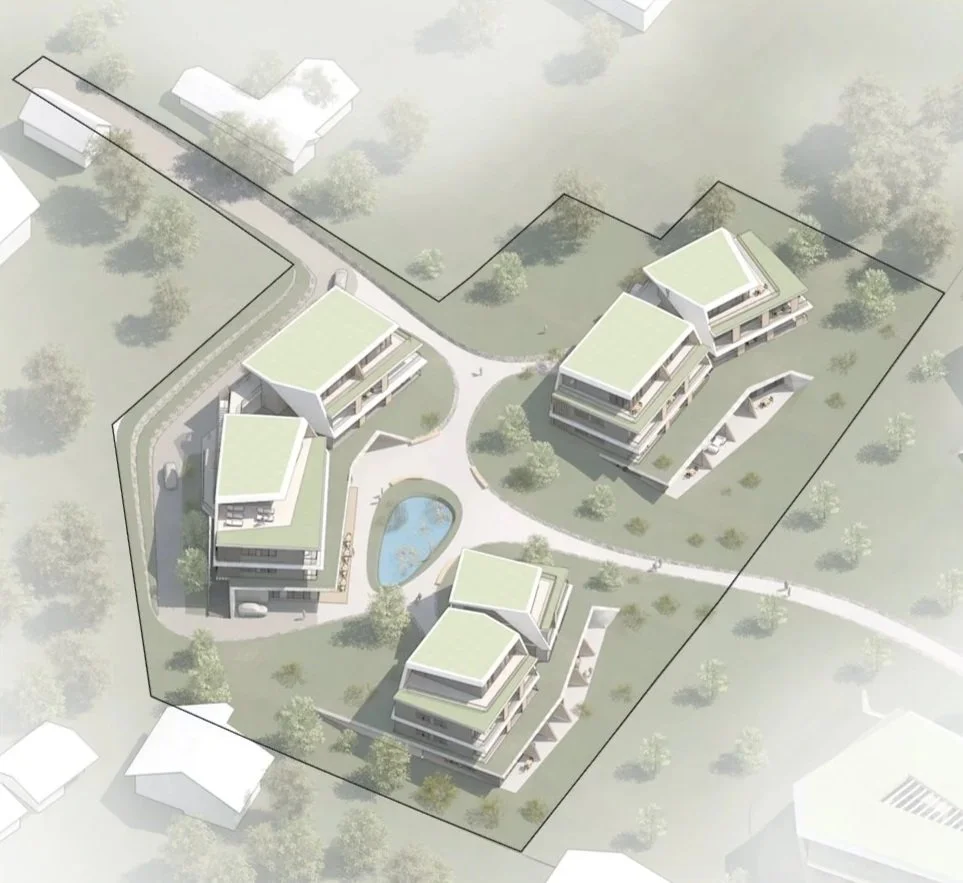 A modern residential complex with balconies and terraces, connected by outdoor staircases and surrounded by landscaped greenery and a small pool. In the background, there is a large building with a green roof.